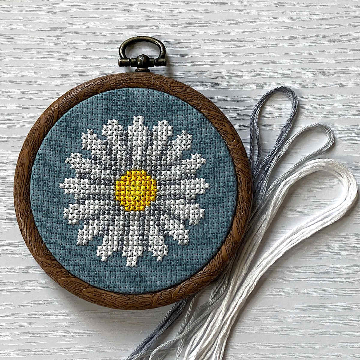 Daisy cross stitch on blue zweigart fabric with DMC threads