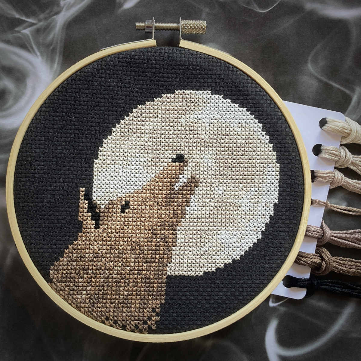 Cross stitch of moonlit wolf howling at full moon