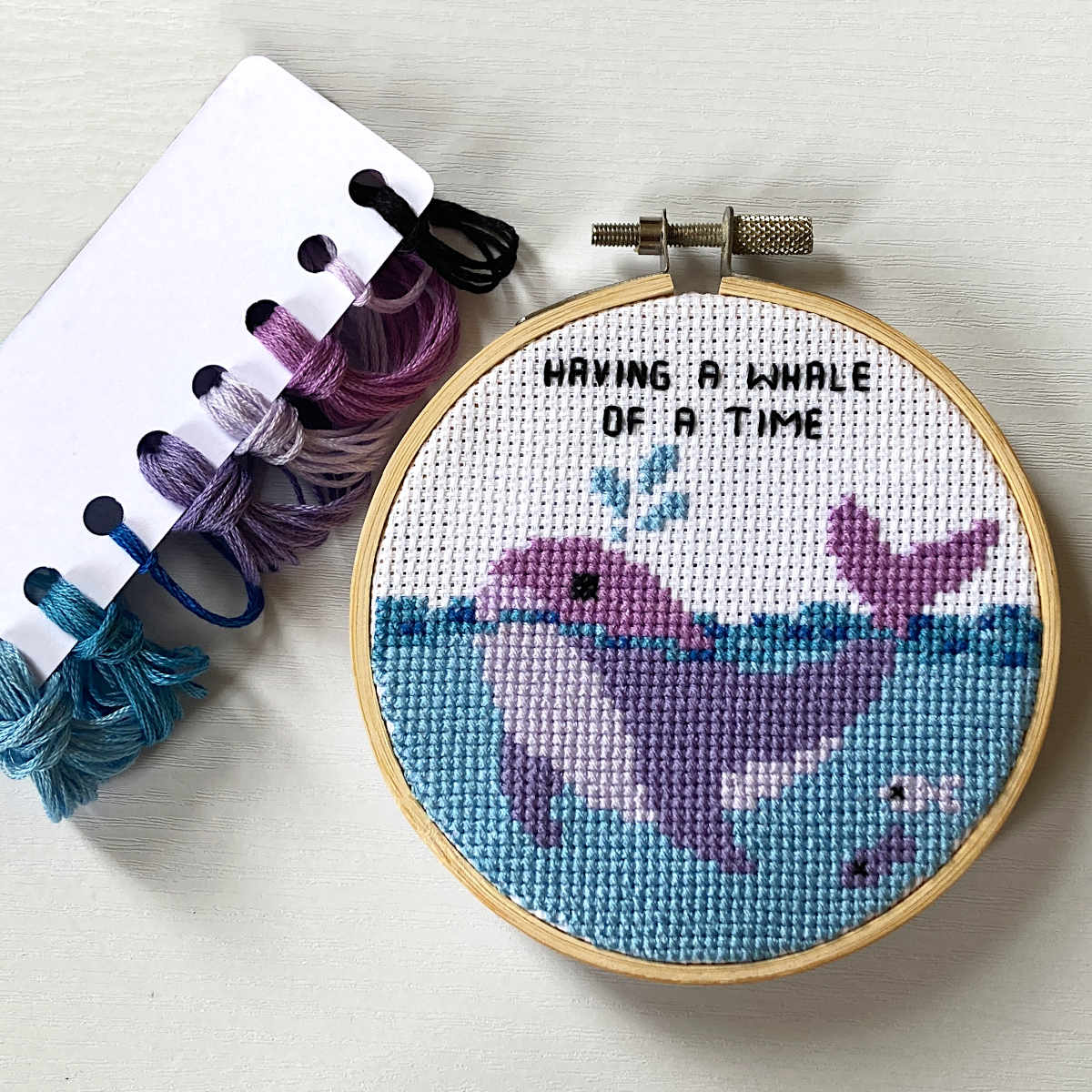 Purple whale cross stitch with 'having a whale of a time' caption in backstitch