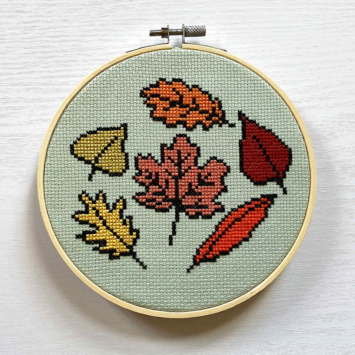 Seasonal cross stitch of autumn/fall leaves on green fabric
