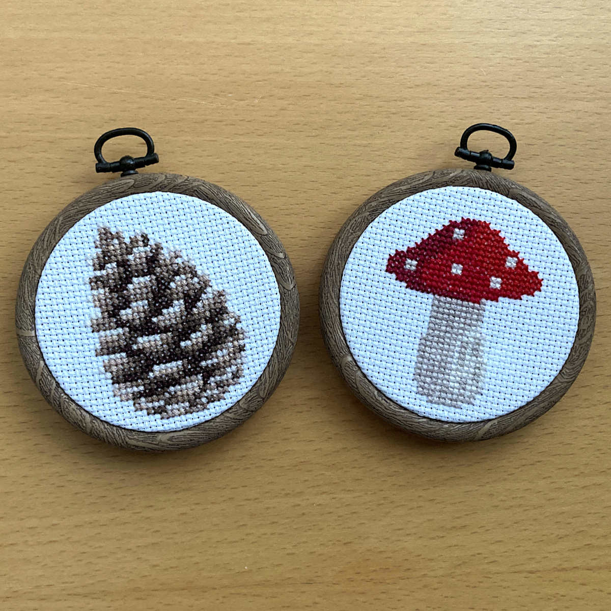 pine cone and red mushroom mini cross stitch in woodgrain flexi embroidery hoops