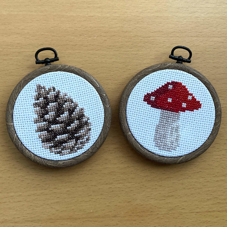 pine cone and red mushroom mini cross stitch in woodgrain flexi embroidery hoops