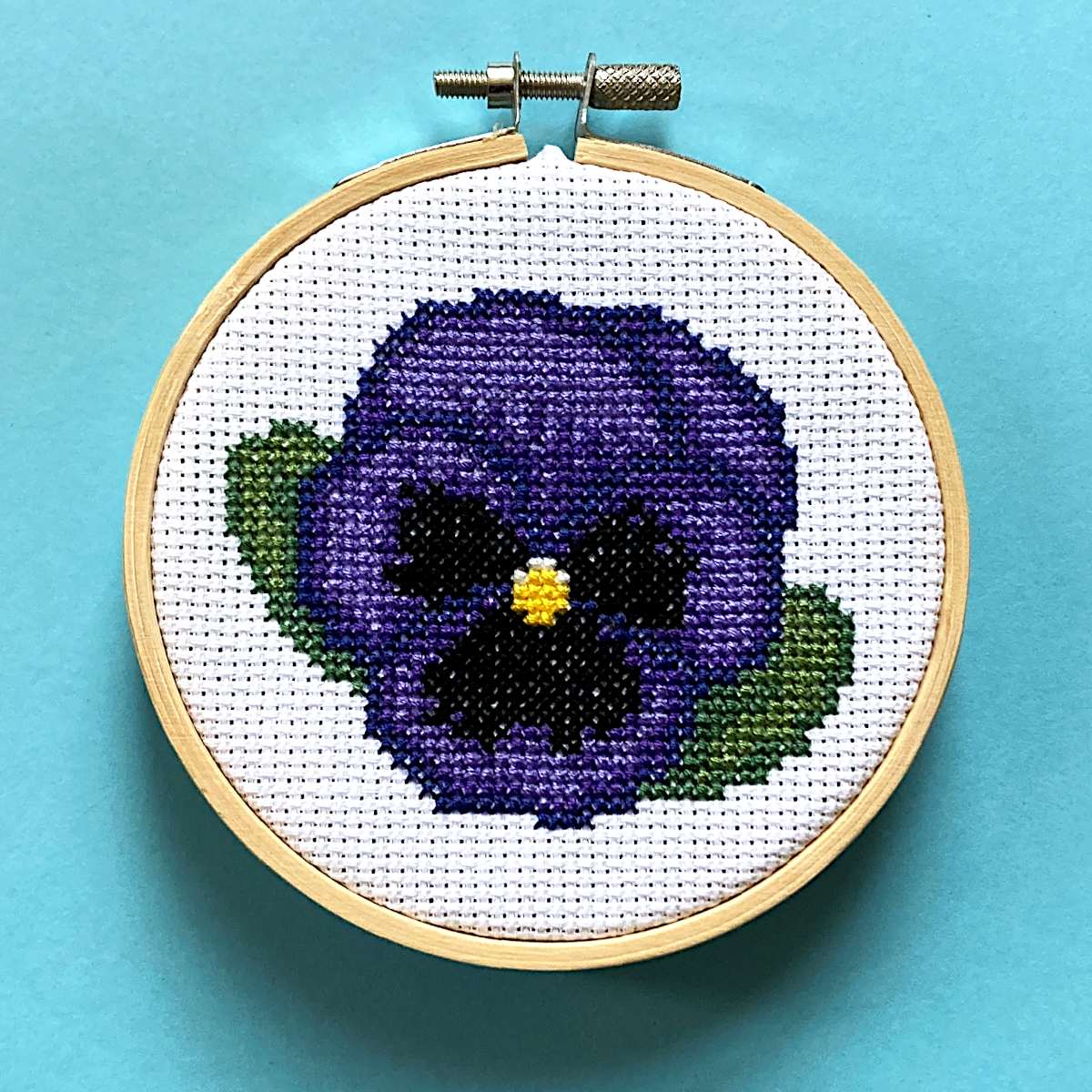 blue-purple pansy cross stitch in hoop