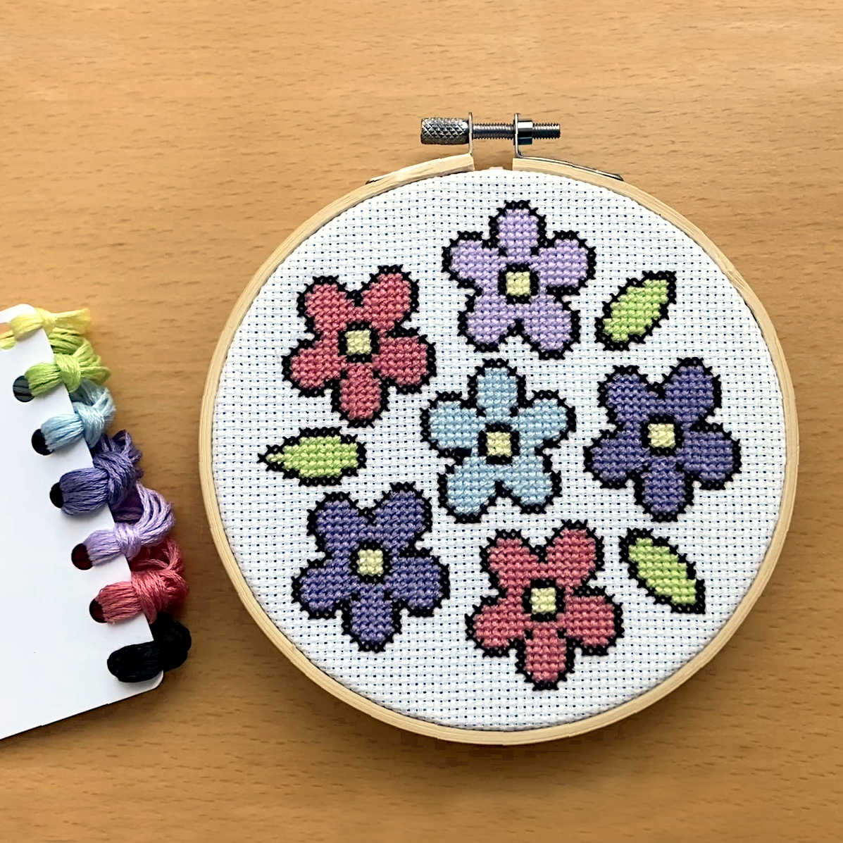 simple flower cross stitch pattern featureing 6 flowers in pink, blues & lilac