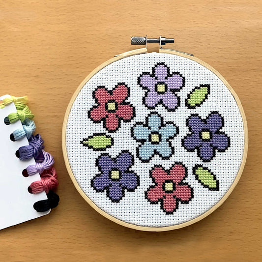 simple flower cross stitch pattern featureing 6 flowers in pink, blues & lilac