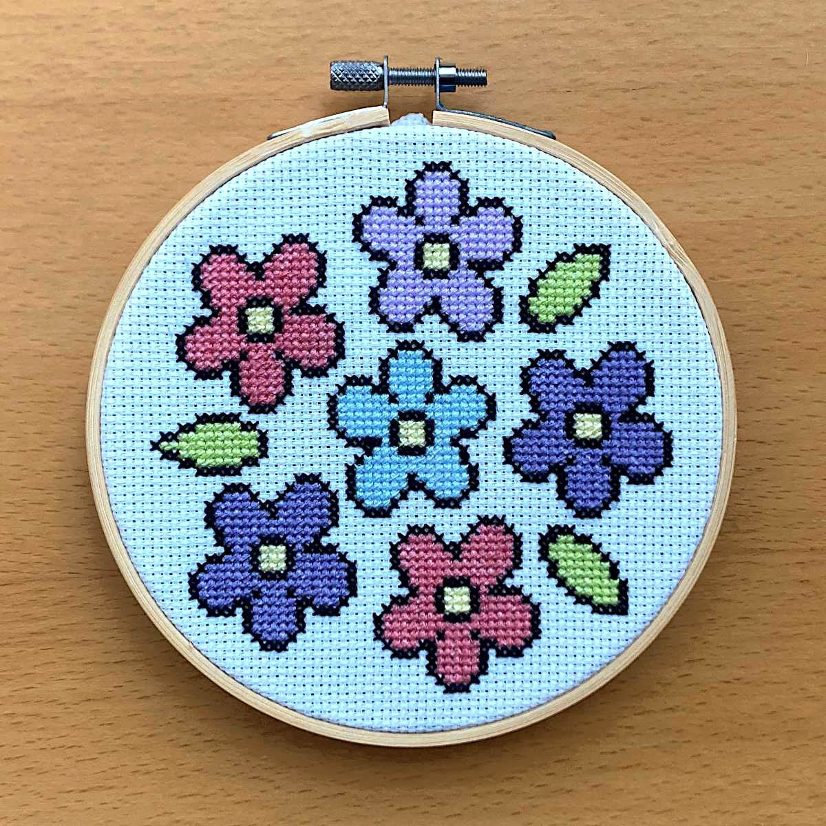 simple flower cross stitch pattern featureing 6 flowers in pink, blues & lilac