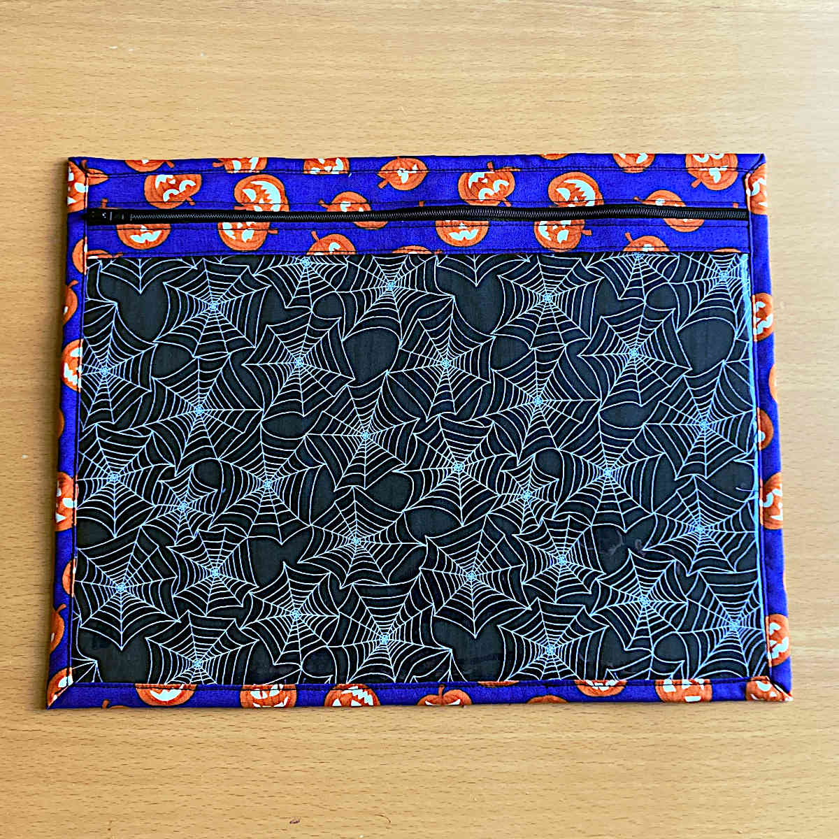 Large project bag front, featuring a zip, Halloween pumpkin fabric, vinyl front and spider web lining fabric