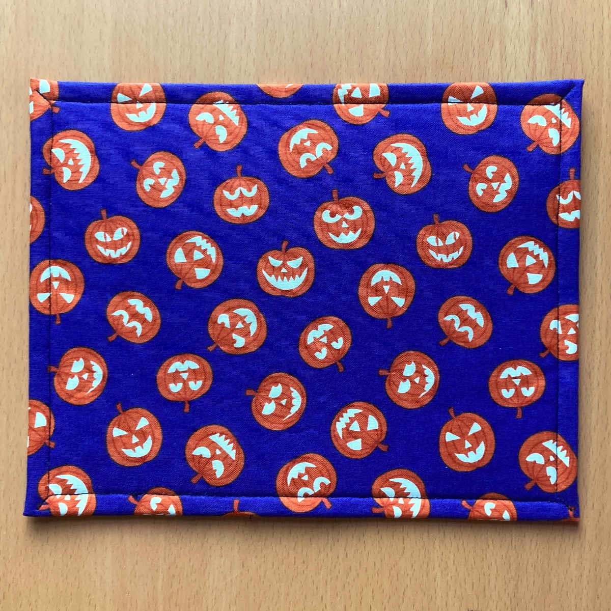 Back of project bag (large option), featuring purple fabric and jack o'lanterns (carved pumpkins)