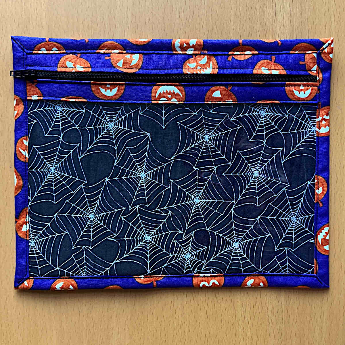 Fabric pouch with Halloween design featuring pumpkins and spider webs on a blue background. (Size - small)