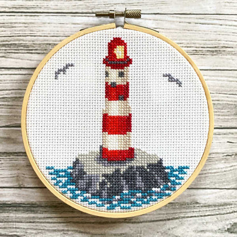 Lighthouse Cross Stitch on rock with ocean in a 5 inch embroidery hoop