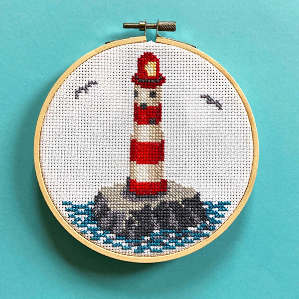 Cross stitch of a lighthouse at sea in a 5 inch hoop