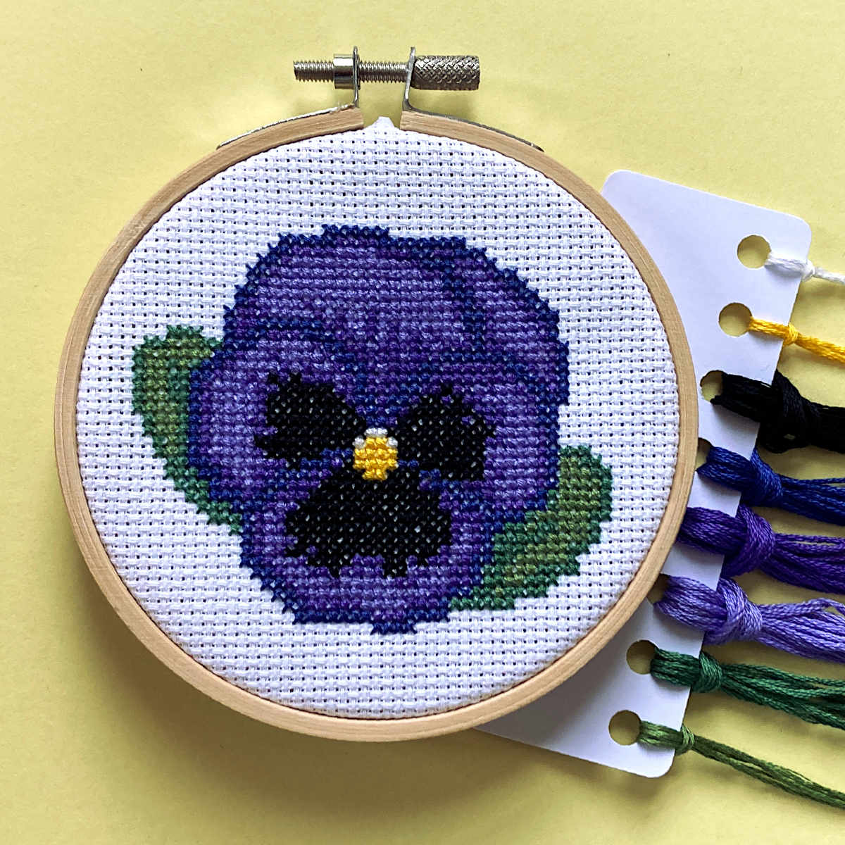 blue pansy cross stitch in embroidery hoop