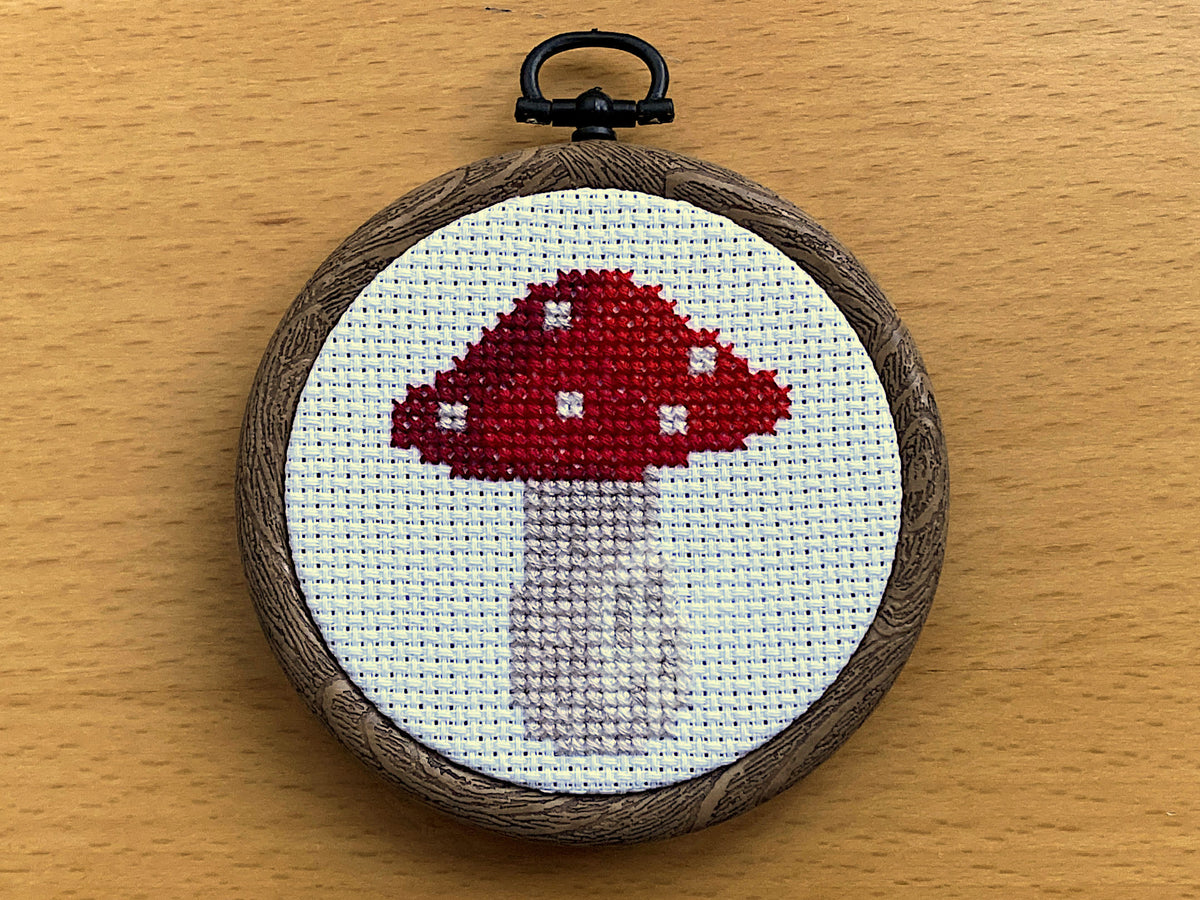 Red toadstool completed mini cross stitch in a small round embroidery hoop