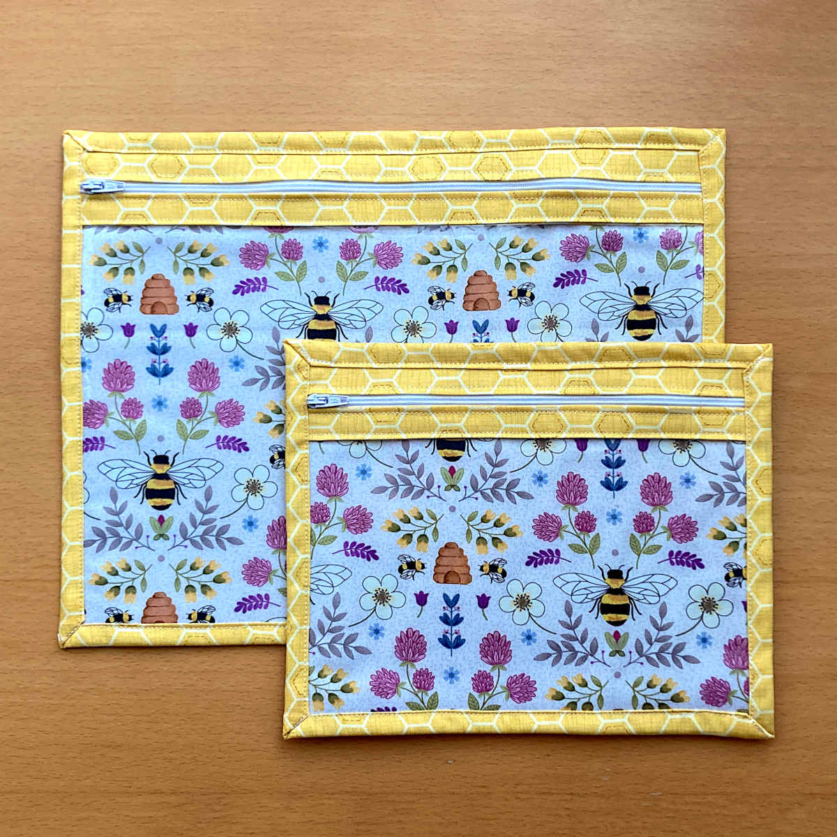 2 Project bags, large and small size, both with yellow honeycomb outer fabric, zip & clear vinyl front with pale blue bee and flower print lining fabric