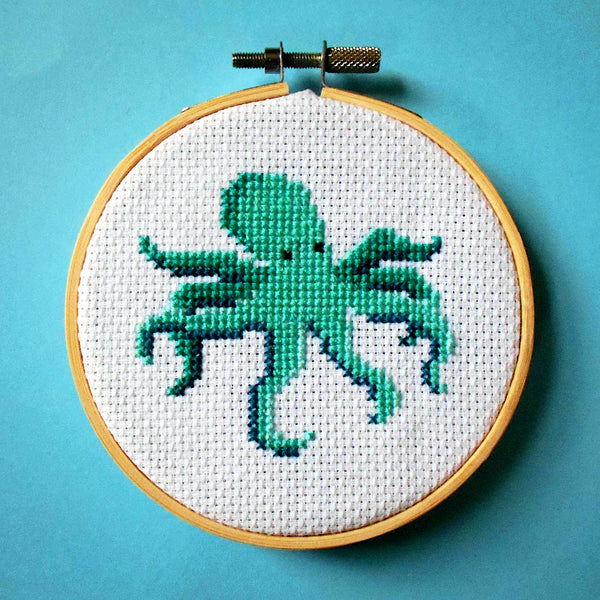 Green-blue octopus cross stitch in wooden embroidery hoop
